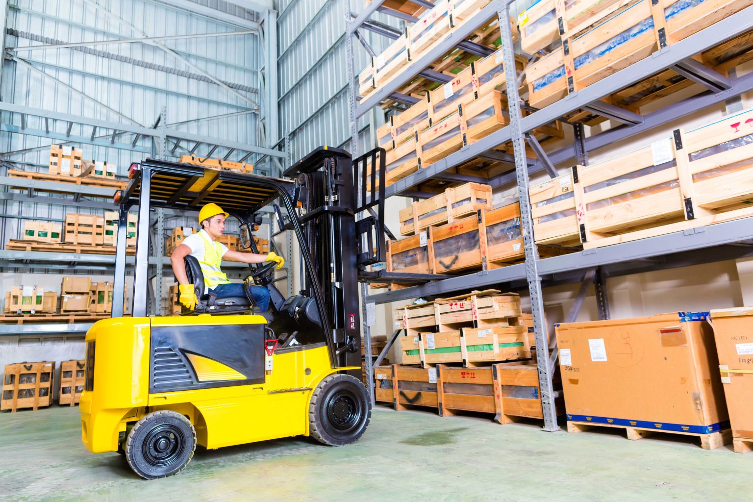 Asian fork lift truck driver lifting pallet in storage | Specialist
